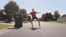 a man in a red shirt is standing in front of a garbage can that says ' veritas ' on the side