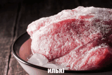 a piece of meat is in a bowl with ice and the letters ilya on the bottom right