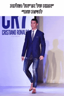 a man in a suit and tie is walking down a runway in front of an ad for cristiano ronaldo footwear