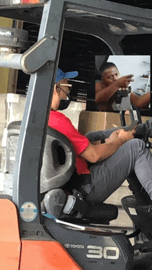 a man in a red shirt sits in a toyota 30 forklift