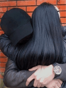 a man wearing a watch is hugging a woman who is wearing a black hat