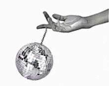 a hand is holding a disco ball with a chain attached to it .