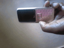 a person is holding a pink cell phone with the numbers 1 through 9 on it