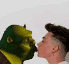 a man is kissing shrek 's face on the cheek .