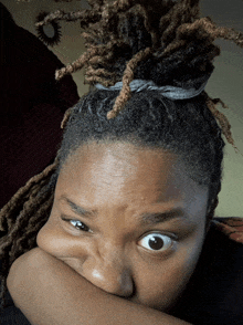 a woman with dreadlocks has her hand on her face