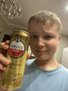 a young boy holds a can of amstel bier