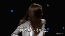 a woman in a suit is sitting in front of a microphone and talking in korean .