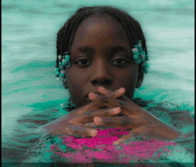 a girl with braids is swimming in a pool with her hands on her face