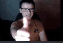 a man wearing glasses giving a thumbs up