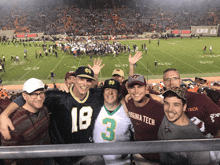 a group of men are posing for a picture in front of a football field