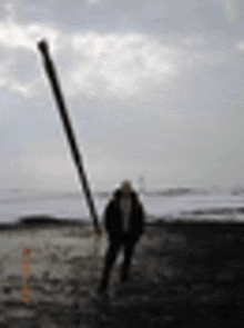 a blurry picture of a person standing next to a pole on the beach .