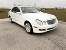 a white mercedes benz e class is parked on the side of the road in a parking lot .