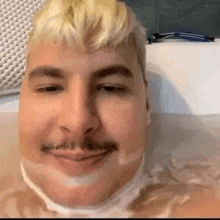 a man with a mustache is taking a bath in a tub .