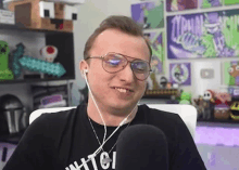 a man wearing glasses and headphones is sitting in front of a microphone in a room .