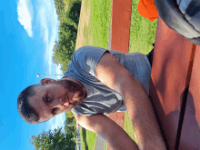 a man with a beard sits at a picnic table in the park