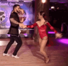 a man and woman are dancing on a dance floor in front of a sign that says sound one union