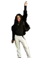 a woman wearing a black jacket and white pants is raising her arm in the air