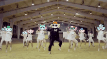 a group of people are dancing in a room with a man wearing a mask with a cat on it