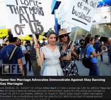 two women holding signs that say people that means all of us and stay banning gay marriages