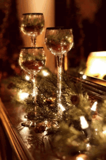 three wine glasses are sitting on a table with christmas decorations