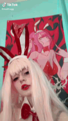 a woman in a bunny costume is taking a selfie in front of a poster of a girl .