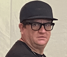 a man wearing glasses and a hat is making a face