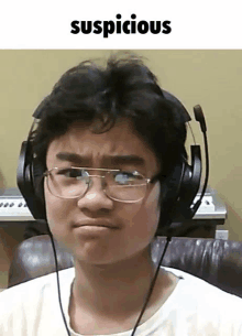 a young man wearing headphones and glasses looks suspicious