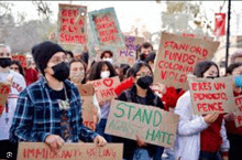 a group of people are holding signs and wearing masks .