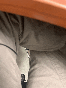 a person sitting under a desk with their pants visible