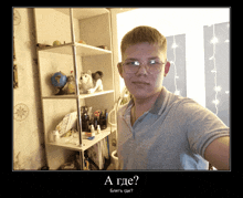 a young man wearing glasses is standing in front of a shelf with the words a gde written on the bottom