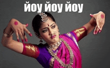 a woman in a pink and purple outfit is dancing in front of a sign that says ioy