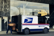 a united states postal service van with a man loading boxes into it