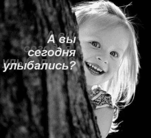 a little girl peeking out from behind a tree trunk and smiling in a black and white photo