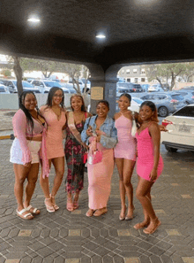 a group of women are posing for a picture in front of a white car