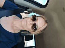 a woman wearing sunglasses sits in a car