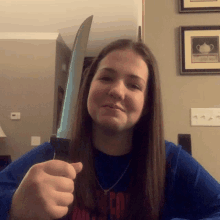 a girl in a blue shirt is holding a knife in her hand