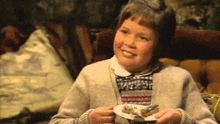 a young girl is holding a plate of food in her hands and smiling