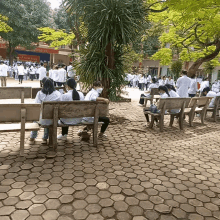 a group of people are sitting on benches in front of a building that says ' lục văn minh ' on it