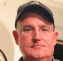 a close up of a man wearing glasses and a baseball cap .