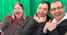 a group of people with down syndrome are posing for a picture in front of a green background .