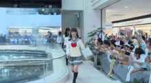 a girl in a sailor uniform is walking in front of a crowd of people