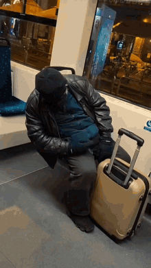 a man sleeping on a bus next to a suitcase with a sticker on the wall that says ' handicap '