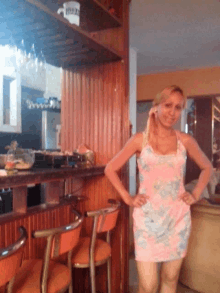 a woman in a pink dress stands in front of a bar with a mug that says pretzel