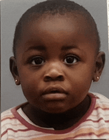 a little girl wearing earrings and a striped shirt is looking at the camera