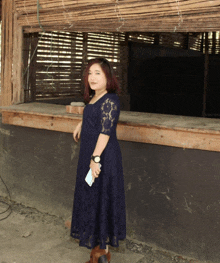 a woman in a blue lace dress is standing in front of a wooden window