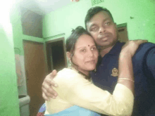 a man and a woman are posing for a picture and the man is wearing a blue shirt with a gold emblem on it