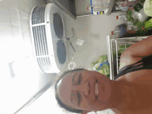 a woman in a black tank top smiles in front of a refrigerator filled with groceries