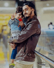 a man in a brown leather jacket is holding a small child