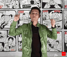 a man in a green jacket is standing in front of a wall with comic strips on it