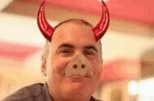 a man wearing devil horns and a fake nose is smiling .